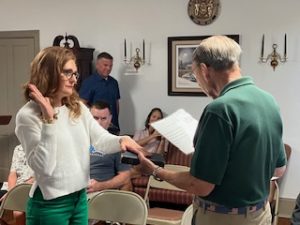 Shelley Perry has one hand in the air and one hand on the bible as Mayor Smith holds the bible facing her and reads her oath of office. 